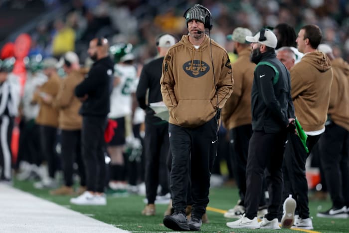 New York Jets injured quarterback Aaron Rodgers walks down the sidelines during a game.